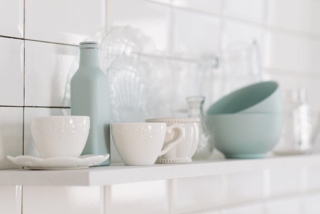 Elegant display of white and pastel kitchen pottery on a shelf in a minimalist style.