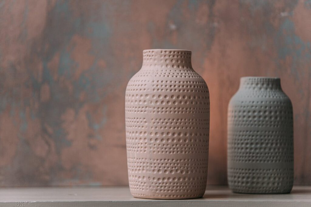 Two handcrafted ceramic vases with textured patterns set against a subtle backdrop.