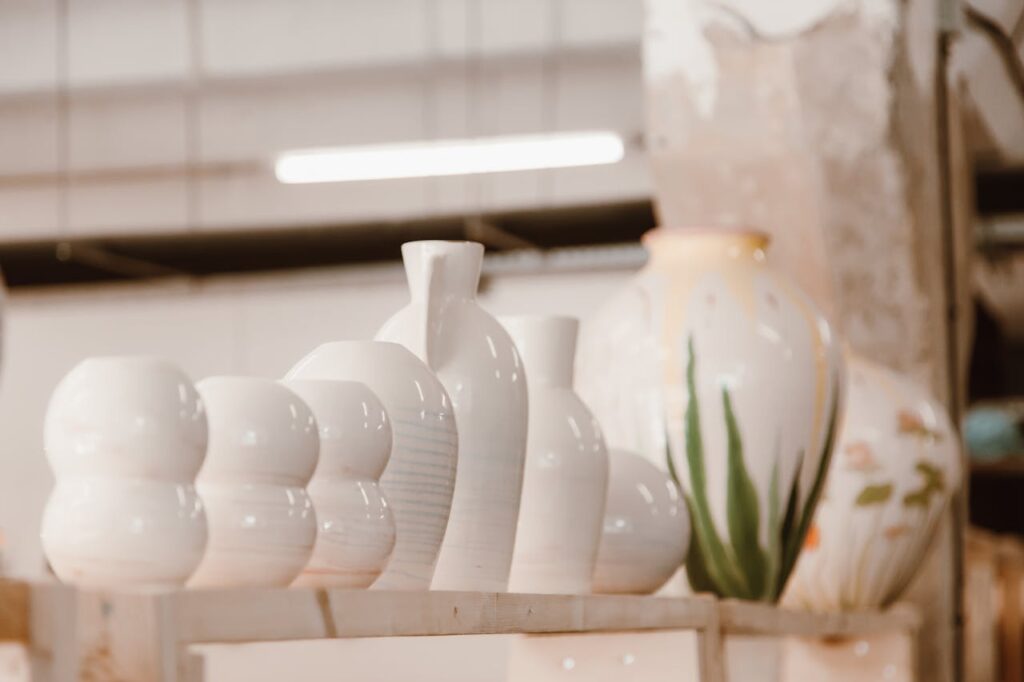 A row of beautifully crafted ceramic vases displayed on a shelf in a pottery studio, highlighting their elegant shapes and glazing.
