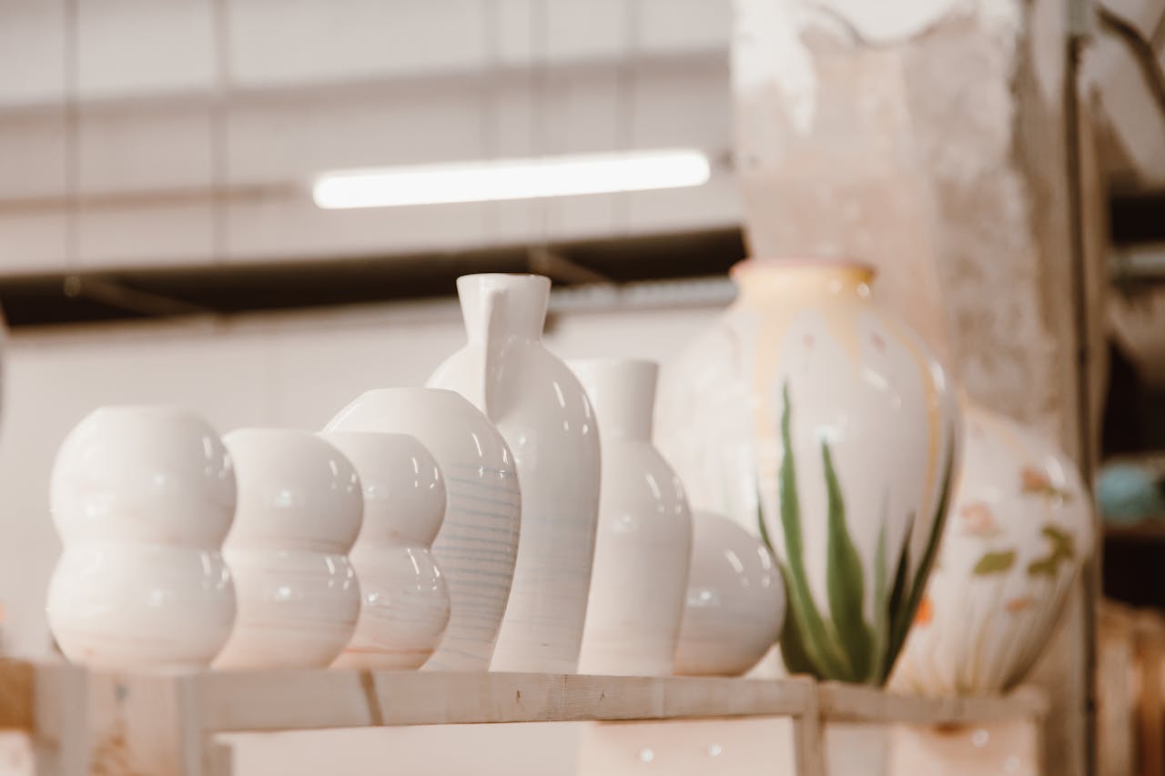 A row of beautifully crafted ceramic vases displayed on a shelf in a pottery studio, highlighting their elegant shapes and glazing.